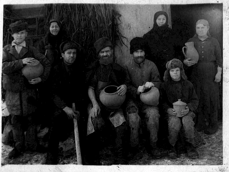 Обухівські гончарі у дворі Векли Калашник (стоїть ліворуч); праворуч сидить підліток &ndash; Кленус Ваня, коло нього з бородою по-вуличному дід Янич; сидить перший ліворуч Олекса Хабрика. Кінець 1930-х- поч. 1940-х років